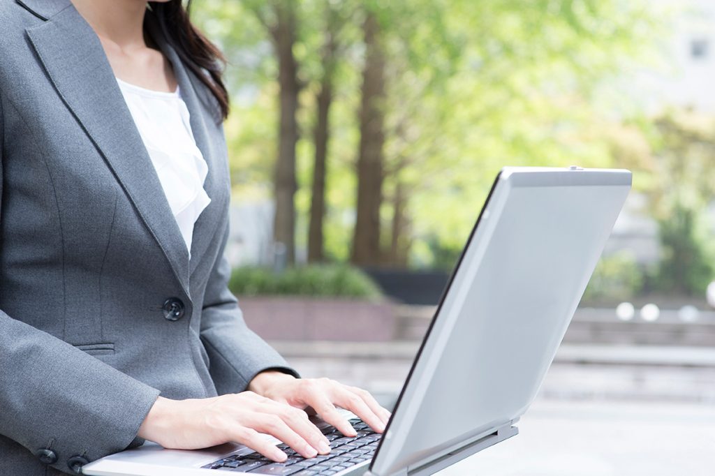屋外でノートPCを操作している女性