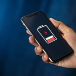 電池残量の少ないスマートフォンを持る手元