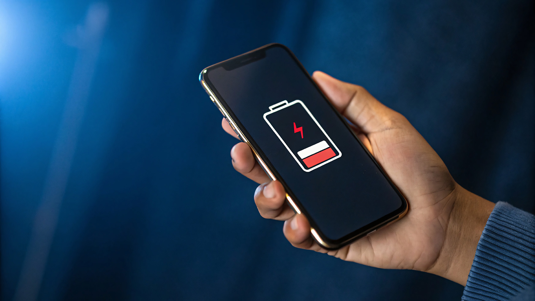電池残量の少ないスマートフォンを持る手元