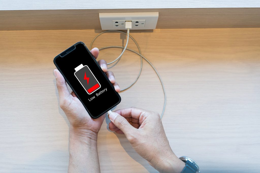 電池残量の少ないスマートフォンに充電ケーブルを指す手元